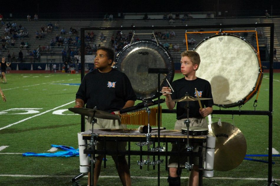 Playing the triangle and cymbal, he also plays the chimes, tamborine, and the bass drum, gong, and cymbal you see behind him